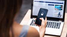 Woman holding a phone with a lock symbol near a laptop with a dashboard screen