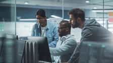 Focused team working together on screens in a modern IT workspace