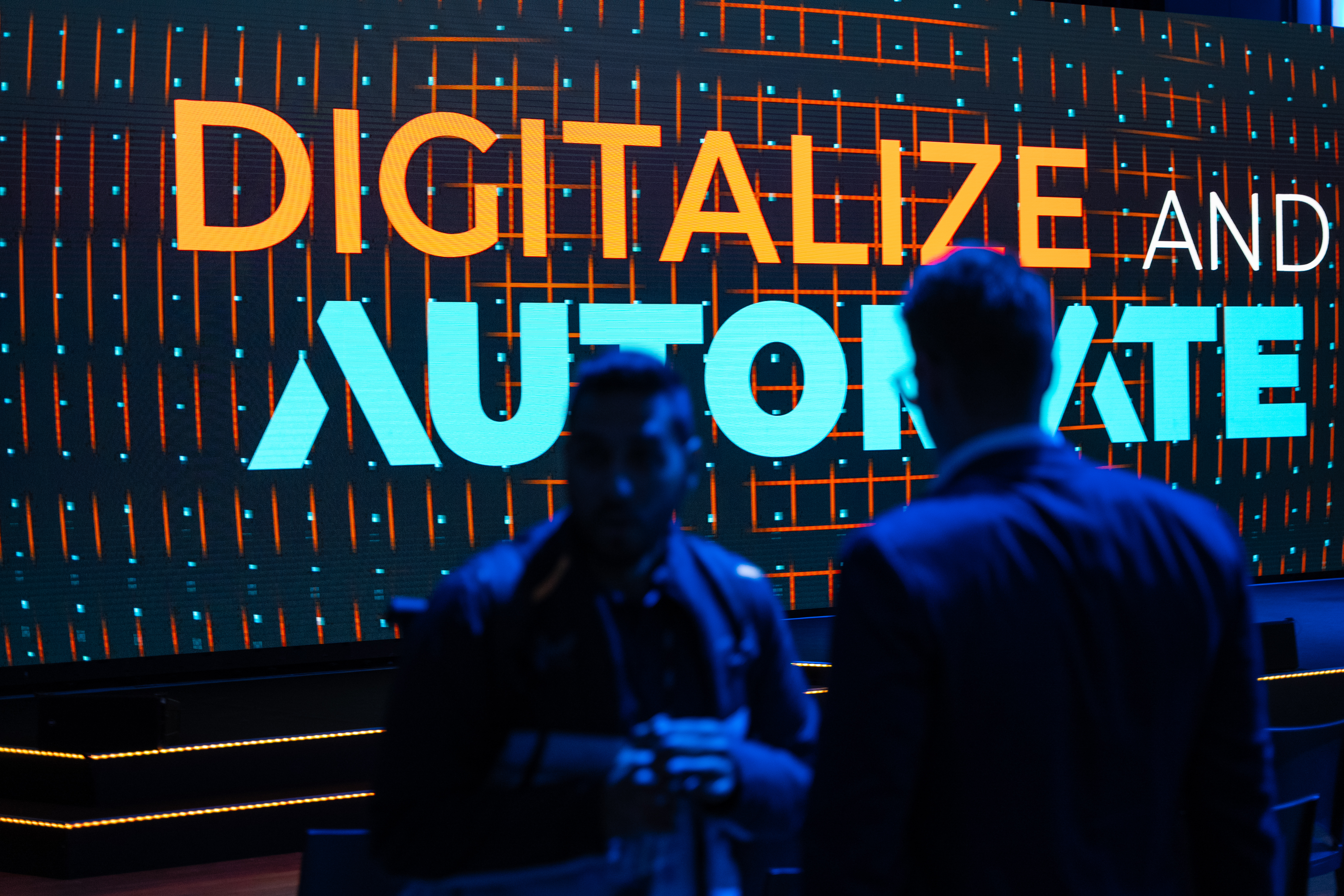 Two men standing in front of the Digitalize And Automate logo at the event in Frankfurt