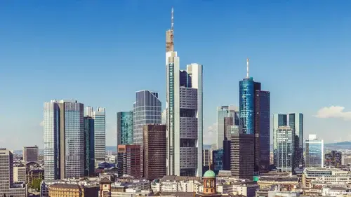 Skyline of Frankfurt with high‑rise office towers and glass façades under a clear blue sky.