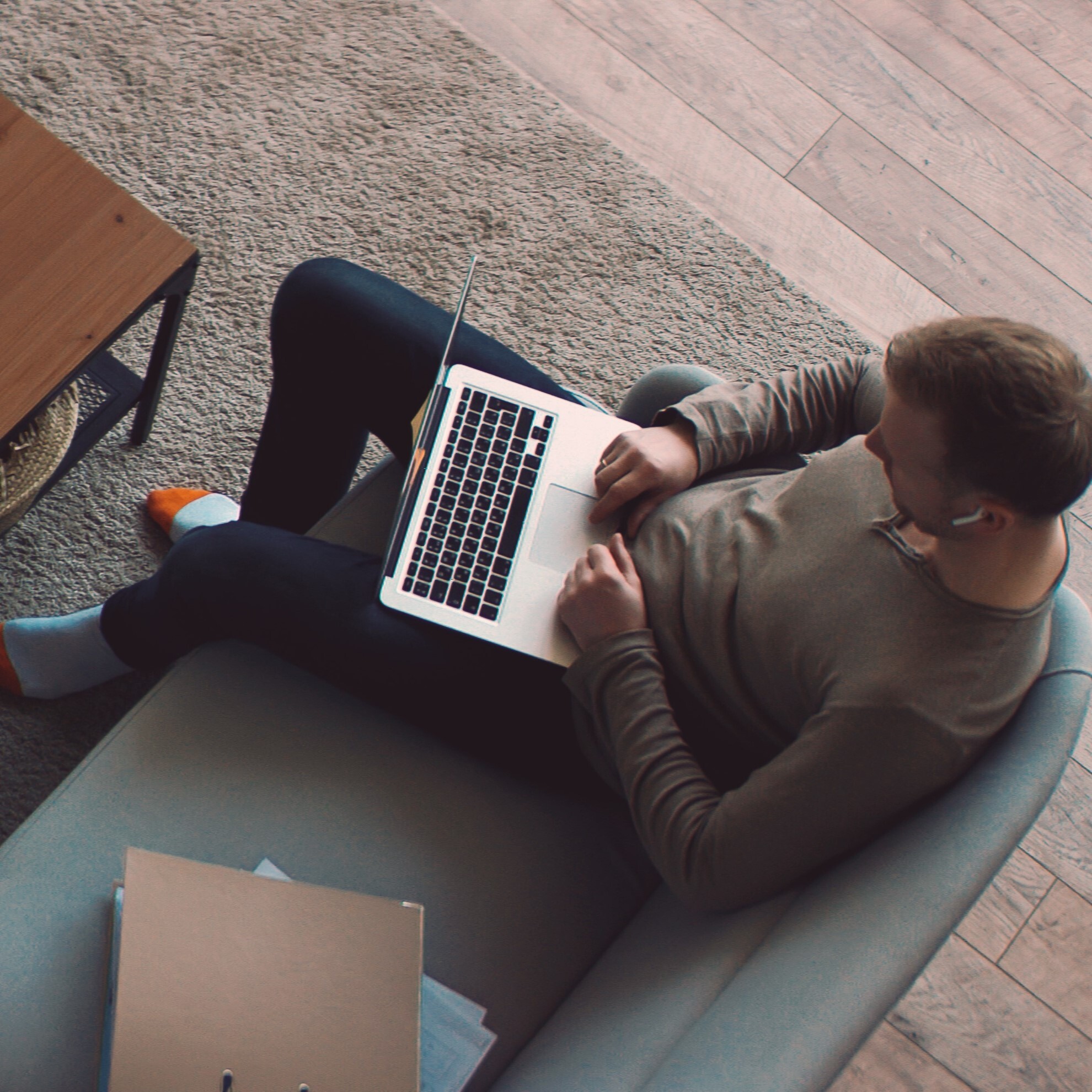 View from above picturing a man sitting on a couch with a laptop on his lap